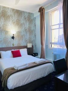 um quarto com uma cama com almofadas vermelhas e uma janela em The Esplanade Hotel em Auckland