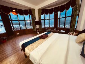 1 dormitorio con 1 cama grande y ventanas grandes en Hotel Hadimba palace en Manāli