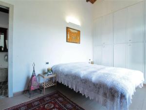 a bedroom with a white bed and a table at Rustic Holiday Home in Montemarzino with Garden in Casasco
