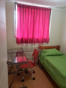 1 dormitorio con escritorio y ventana con cortina rosa en Departamento en Alameda Talca en Talca