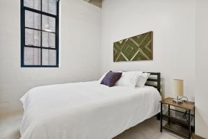 a white bedroom with a white bed and a table at Industrial Loft Apartments in the Beautiful Superior Building Minutes from FirstEnergy Stadium 311 in Cleveland
