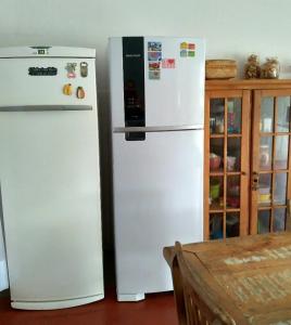 two white refrigerators in a kitchen next to a table at Lindo quarto casal no centro Floripa in Florianópolis