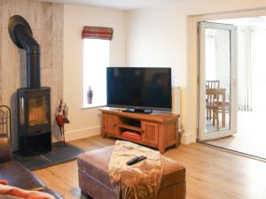 a living room with a flat screen tv and a wood stove at Townend Cottage in Aikton