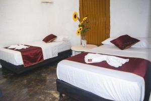 two beds in a room with a vase of sunflowers at Hostel Tatacoa in Villavieja