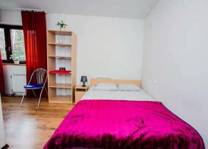a bedroom with a large bed with a red blanket at Apartamenty Motylem Jestem in Szczawnica
