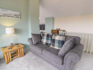 a living room with a gray couch and a table at Bryn Goleu in Moelfre