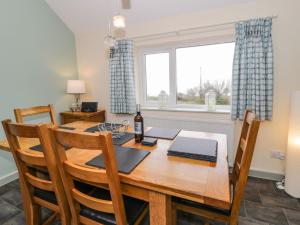 a dining room with a wooden table and a window at Bryn Goleu in Moelfre