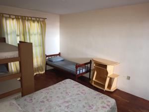 a bedroom with a bunk bed and a table and a bench at Casa da Frente Santa Felicidade in Curitiba