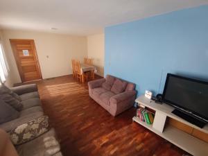 a living room with two couches and a flat screen tv at Casa da Frente Santa Felicidade in Curitiba