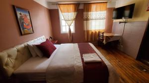 a bedroom with a large bed with a couch and a television at Hostal Bolívar Inn in Quito