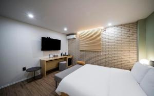 a bedroom with a bed and a tv on a brick wall at Hotel Yaja Changwon Myeongseo in Changwon