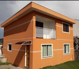 a small orange house with a balcony on top at Casa da Frente Santa Felicidade in Curitiba