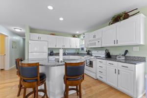 una cocina con armarios blancos y una barra con sillas en The Lake House Home en Rockaway Beach