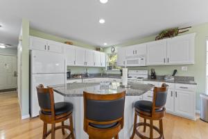 a kitchen with white cabinets and a island with bar stools at The Lake House Home in Rockaway Beach