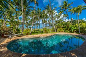 una piscina frente a un complejo con palmeras en Halama Hale Private Home home, en Kihei