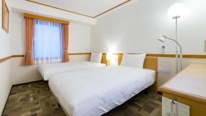神戸市にある東横INN神戸三ノ宮1のベッド2台と窓が備わるホテルルームです。