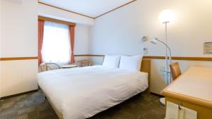 a hotel room with a white bed and a window at Toyoko Inn Kumamoto Sakuramachi Bus Terminal Mae in Kumamoto