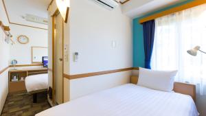 a bedroom with a bed and a desk and a window at Toyoko Inn Yokohama Stadium Mae No 1 in Yokohama