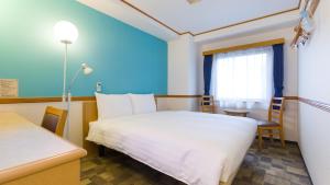 横浜市にある東横INN横浜スタジアム前1のベッド、テーブル、窓が備わる客室です。
