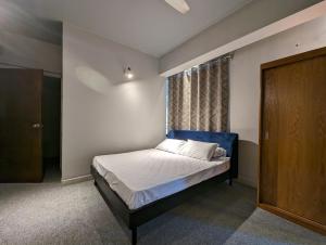 ein Schlafzimmer mit einem Bett mit blauem Kopfteil und einem Fenster in der Unterkunft GreyRooms in Dhaka