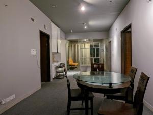 ein Esszimmer mit einem Glastisch und Stühlen in der Unterkunft GreyRooms in Dhaka