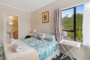 a bedroom with a bed and a window and a desk at Riverside Accommodation in Karangahake