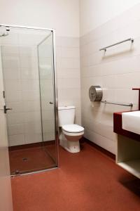 a bathroom with a toilet and a glass shower at Bellarine Lodge Sleeps 30 in Drysdale