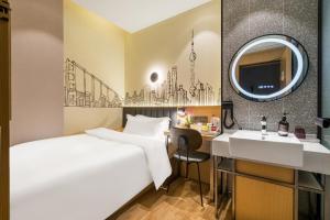 上海市にあるMeego Smart Select Hotelのベッド、シンク、鏡が備わるホテルルームです。