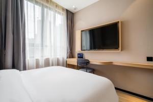 a hotel room with a bed and a flat screen tv at Meego Smart Select Hotel in Shanghai