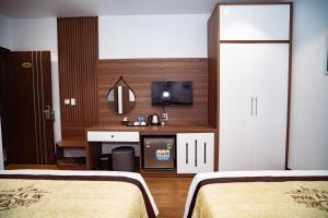 ハロンにあるNavy Hotel Ha Longのベッド2台、デスク、テレビが備わるホテルルームです。