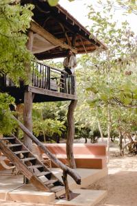 a man sitting on a porch of a tree house at Hilltop Cabanas in Komari
