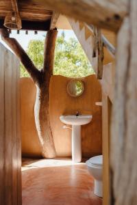 a bathroom with a sink and a tree shaped mirror at Hilltop Cabanas in Komari