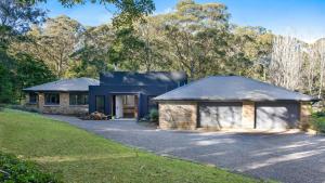 a house with a garage in the middle of a driveway at The Gullies Retreat in Bundanoon