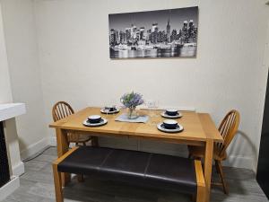 einen Holztisch mit Stühlen und ein Bild einer Stadt in der Unterkunft Skyline Queen's suites 203 in Swansea