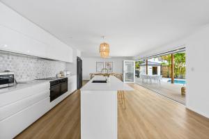 an open kitchen with white cabinets and a kitchen island at Luxury home in the heart of Burleigh in Gold Coast