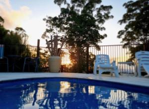 a swimming pool with chairs and a vase on a fence at Mahalo BnB in Mapleton
