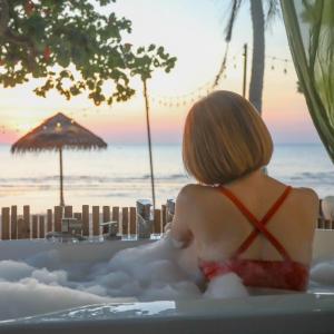 a woman sitting in a bath tub with the ocean at Beach House Camp in Na Jomtien