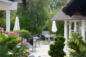un patio con mesas, sillas y sombrillas blancas en Havgaarden Badehotel en Vejby