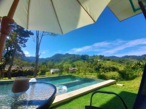 a table with an umbrella next to a swimming pool at The Hill in Kampong Sum Sum