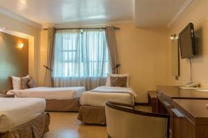 a hotel room with two beds and a television at Summerdale Inn in Nairobi