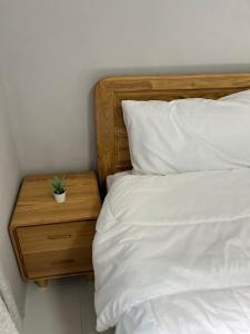 a bed with white sheets and a wooden nightstand with a plant on it at บ้านอยู่สบาย บึงโขงหลง in Ban Don Klang
