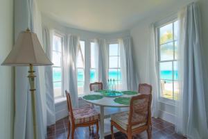 a dining room with a table and chairs and windows at Folly home in Governorʼs Harbour