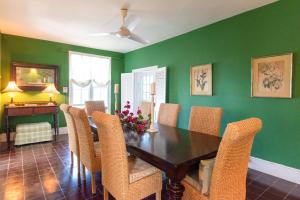 a dining room with green walls and a wooden table and chairs at Folly home in Governorʼs Harbour