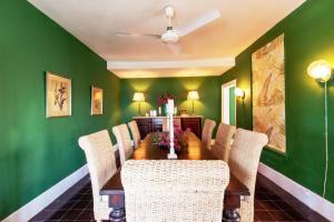 a dining room with green walls and a table with chairs at Folly home in Governorʼs Harbour