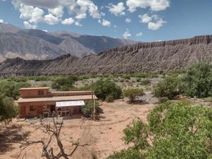 un bâtiment dans le désert avec des montagnes en arrière-plan dans l'établissement Cabaña Misk'i Nuna, en las afueras de Tilcara, à Tilcara