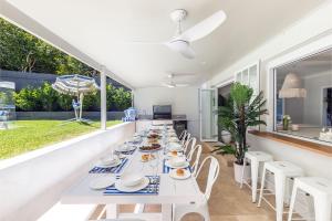 een eetkamer met een lange witte tafel en stoelen bij Cloud Nine 18 Wynne Crescent in Corlette