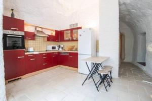 cocina con armarios rojos y nevera blanca en Maison troglodyte - Le Cerisier Perché en Luynes