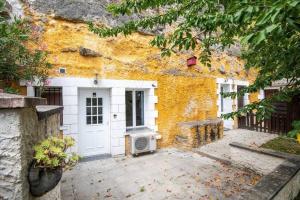 un edificio amarillo con una puerta blanca y un patio en Maison troglodyte - Le Cerisier Perché, en Luynes