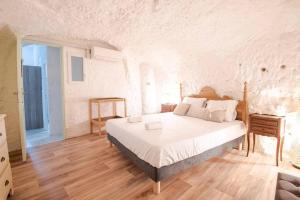 Maison troglodyte - Le Cerisier Perché في Luynes: غرفة نوم بسرير كبير في غرفة بيضاء