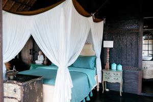 a bedroom with a blue bed with a canopy at Most Exotic Villa Keong in Tabanan